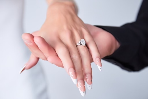 Close-up bridal French tip almond nails with crystal dots and diamond engagement ring by ManiBliss Organic Nails and Spa